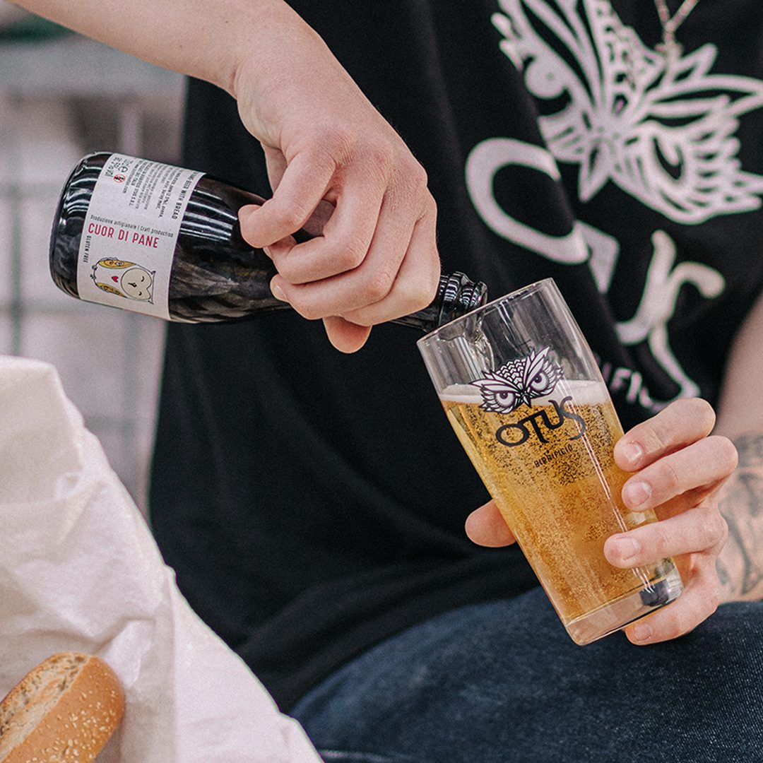 Birra artigianale Otus Cuor di Pane, stile Helles, servita in un bicchiere con il logo del birrificio