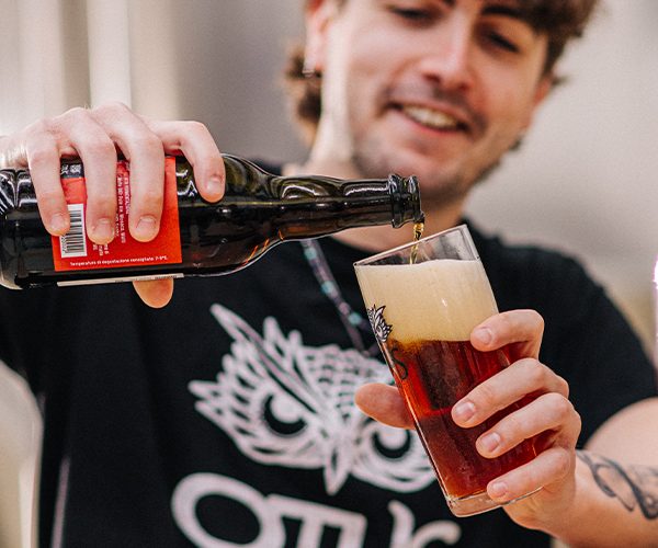 Birra artigianale Otus versata in un bicchiere da una bottiglia