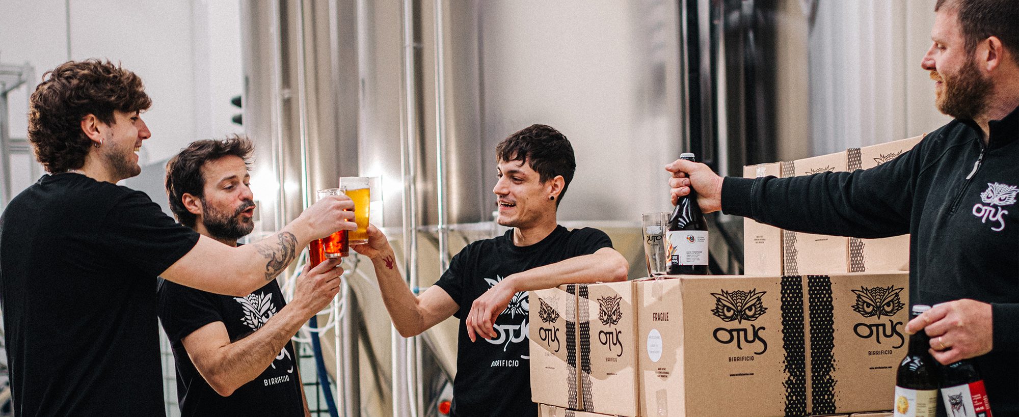 Team del birrificio Otus brinda tra i fermentatori in acciaio del laboratorio